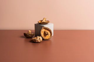 Image of fresh shiitake mushrooms arranged gracefully on and around a pedestal, showcasing their natural brown caps and white stems in a well-lit setting that emphasizes the mushrooms' texture and organic quality