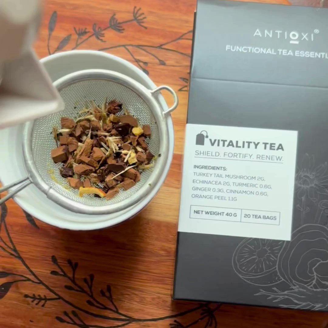 Antioxi Vitality Mushroom Tea box next to a tea strainer filled with loose leaf ingredients, highlighting its blend of Turkey Tail mushroom, echinacea, turmeric, ginger, cinnamon, and orange peel.