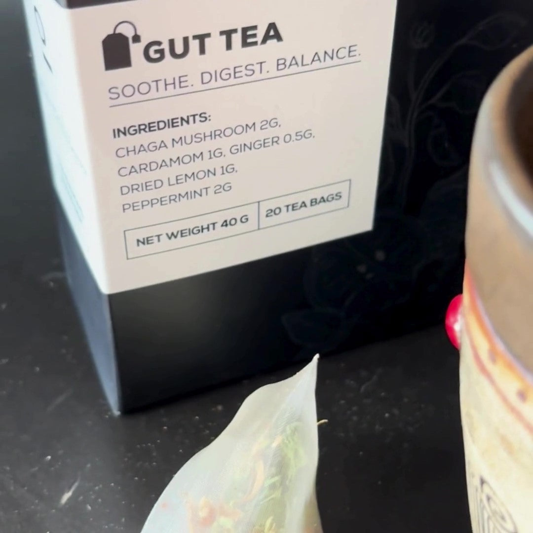 A close-up of Antioxi Gut Mushroom Tea tea-box next to a partially visible cup and tea-bag, highlighting the product's ingredients listed on the box.