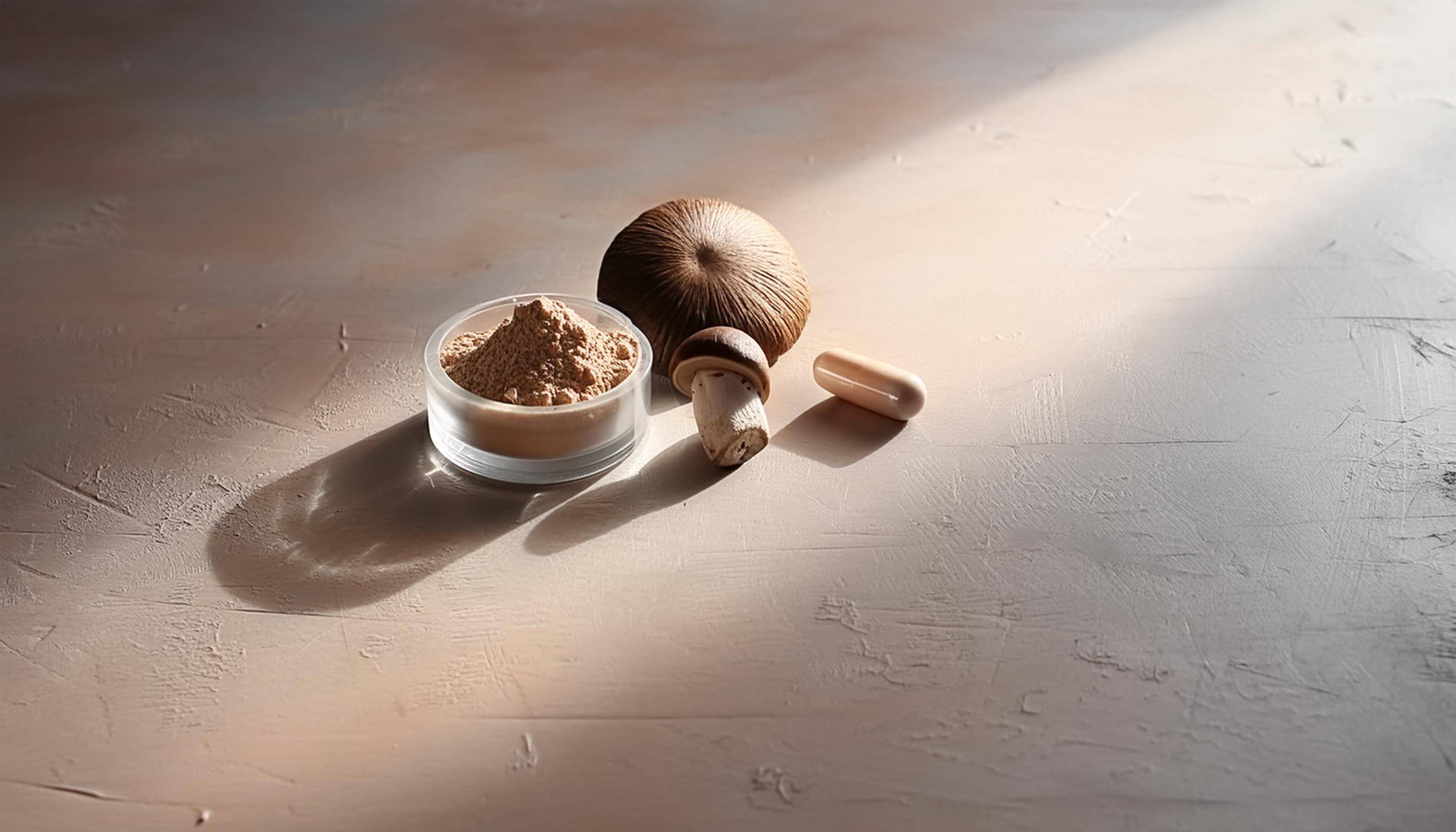 Two shiitake mushrooms beside a glass jar filled with shiitake mushroom extract powder, with a brown capsule of mushroom extract nearby, set against a light, muted pink or peach background.