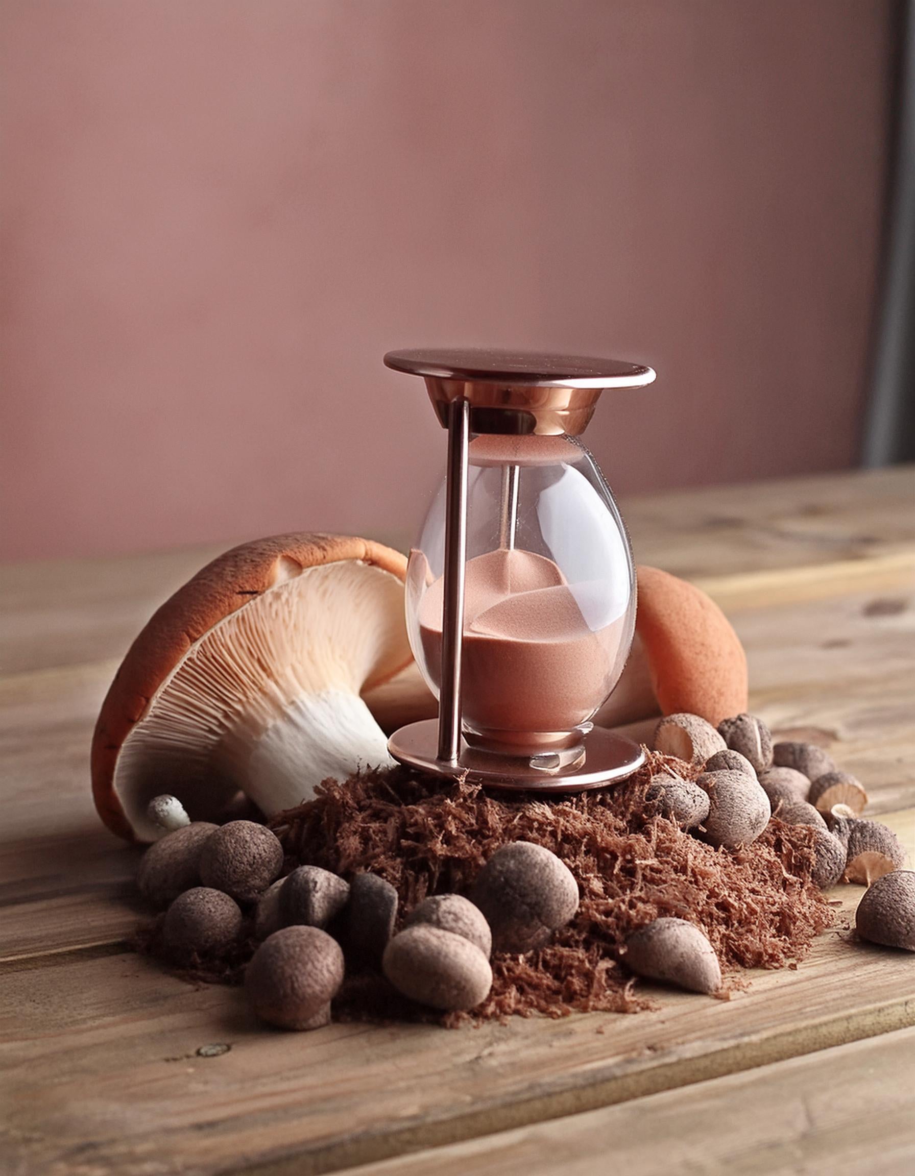 Hourglass on a heap of brown mushroom powder extract, symbolizing support for menopause health